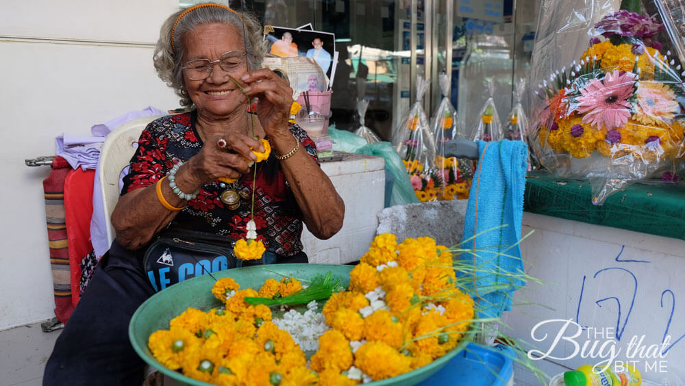 an elderly woman strings flowers