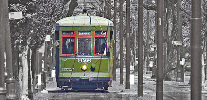 green streetcar moves along the tracks, background is black and white